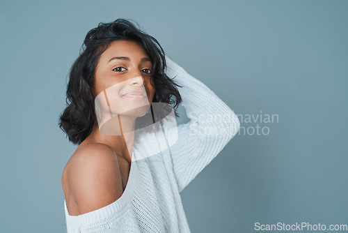 Image of Happy looks good on you. a beautiful young woman posing against a teal background.