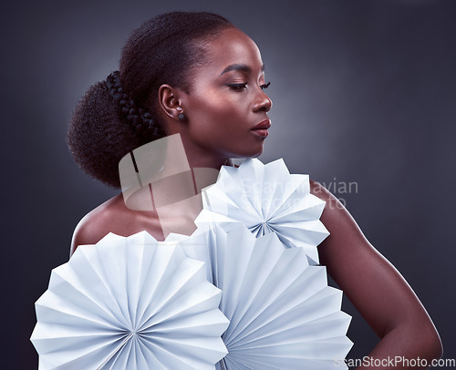 Image of The most attractive people are those that allow their light to shine. Studio shot of a beautiful young woman posing with origami fans against a black background.