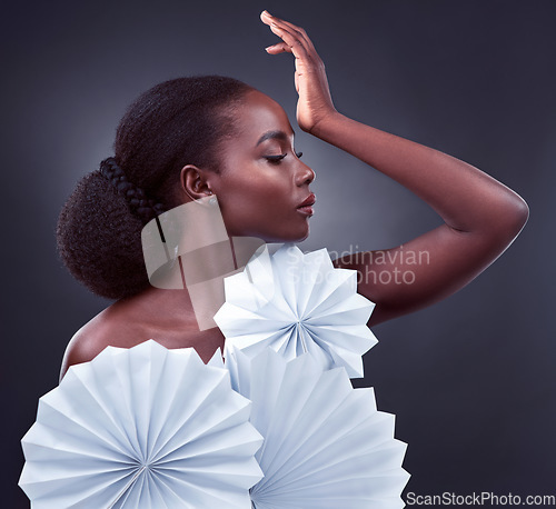 Image of Elegance is beauty that never fades. Studio shot of a beautiful young woman posing with origami fans against a black background.