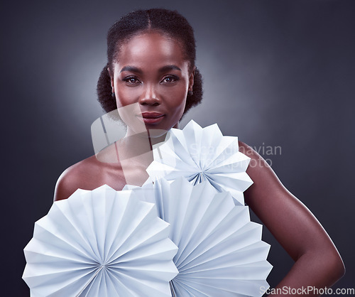 Image of The world needs your light, so keep shining. Studio portrait of a beautiful young woman posing with origami fans against a black background.