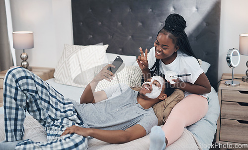 Image of You can stay home and still keep your glow. a young couple taking selfies while getting homemade facials together at home.