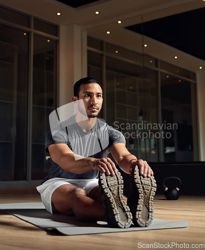 Image of Stretching it out. Full length shot of a handsome young male athlete going through his warmup routine in the gym.