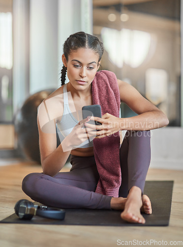 Image of Checking her messages between sets. Full length shot of an attractive young female athlete checking her phone while sitting in the gym.