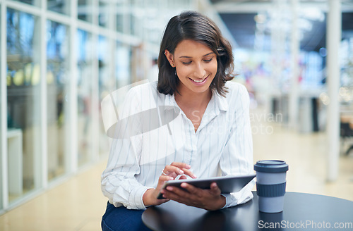 Image of Working through her to dos one tap at a time. a young businesswoman using a digital tablet during a coffee break in a modern office.