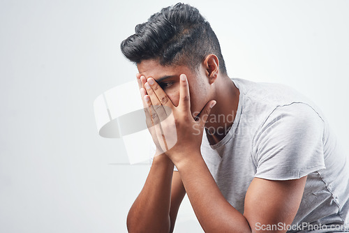 Image of Im not sure how to feel. Studio shot of a young man sitting against a white background.