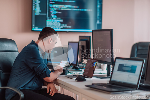 Image of A programmer diligently testing smartphone applications while sitting in their office.