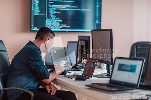 Image of A programmer diligently testing smartphone applications while sitting in their office.