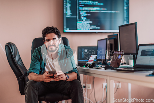 Image of A programmer diligently testing smartphone applications while sitting in their office.