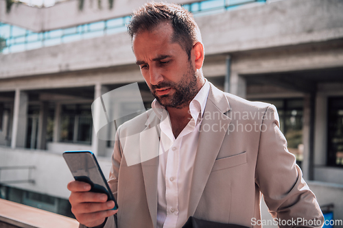 Image of A businessman using his smartphone outdoors, showcasing the seamless integration of technology and mobility in modern professional life.