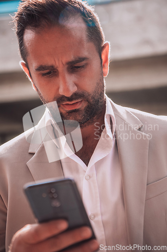 Image of A businessman using his smartphone outdoors, showcasing the seamless integration of technology and mobility in modern professional life.
