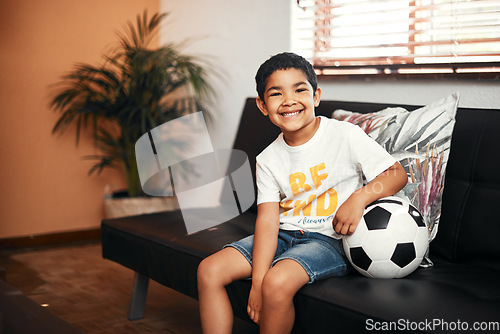 Image of Soccer is so much fun. Portrait of an adorable little boy sitting with a soccer ball on the sofa at home.
