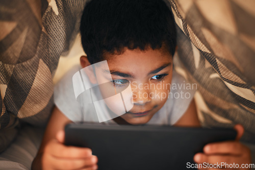 Image of Hes too curious to sleep. an adorable little boy using a digital tablet while lying under a blanket at home.