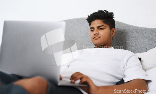 Image of The internet is a plethora of entertainment. an young man using his laptop while lying on his bed.