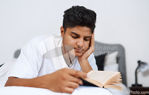 Image of Ive been reading a lot lately. a young man reading a book while lying on his bed.