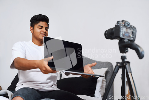Image of Use my code and youll get discount. a young man using a camera on a tripod to record himself at home.