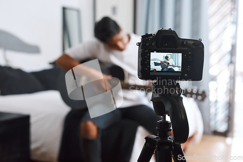 Image of Im doing another cover. a young man recording himself at home while playing the guitar.