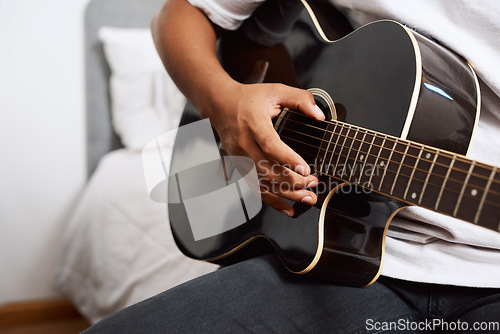 Image of It requires patience, perseverance and dedication. a young man playing the guitar while sitting at home.
