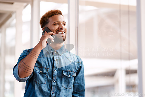 Image of Business relationships are the key to success. a handsome young male designer making a phonecall while standing at at a window in his office.