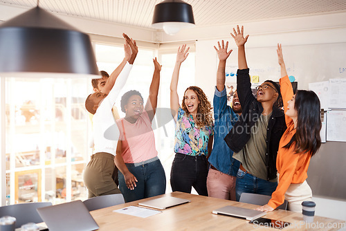 Image of Celebrating greatness. a group of young designers raising their hands in celebration while standing in the boardroom of their office.