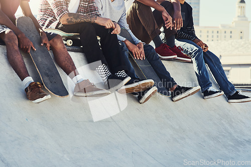 Image of Kicking back at the skatepark. a group of unrecognizable skaters sitting together on a ramp at a skatepark.