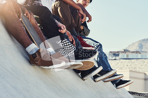 Image of We have the whole world at our feet. a group of unrecognizable skaters sitting together on a ramp at a skatepark.