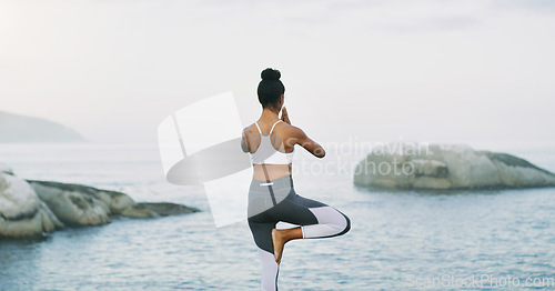 Image of Yoga is a life source to me. Rearview shot of an unrecognizable woman standing and doing yoga alone by the ocean during an overcast day.