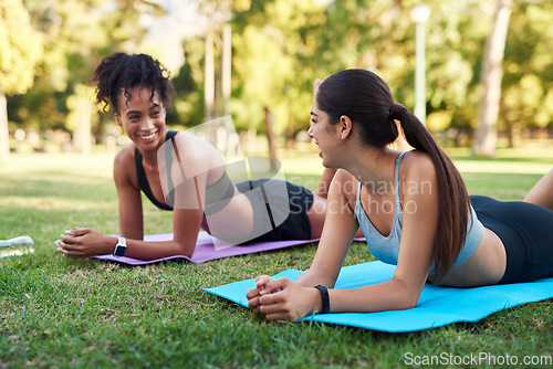 Image of Taking a moment to breathe. two attractive young women stretching next to each other in the park during the day.