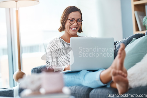 Image of My blog is getting more and more followers. Full length shot of a happy young woman using a laptop while relaxing in her living room.