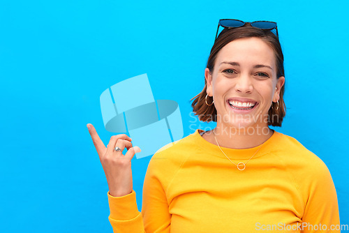 Image of Ive got a new exciting idea up here. Cropped portrait of a happy young woman pointing up against a blue background.