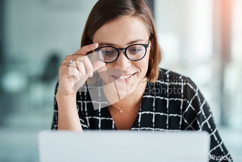 Image of The numbers are starting to look good. a happy young businesswoman working on a laptop in an office.