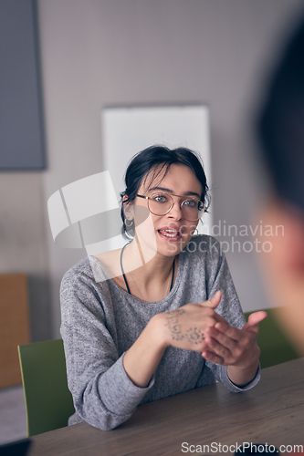 Image of In a modern office, a young smile businesswoman with glasses confidently explains and presents various business ideas to her colleagues, showcasing her professionalism and expertise.