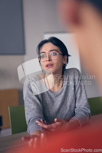 Image of In a modern office, a young smile businesswoman with glasses confidently explains and presents various business ideas to her colleagues, showcasing her professionalism and expertise.