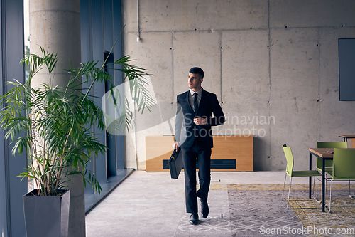 Image of A confident businessman with a briefcase strides through a modern office, exuding charisma and determination, symbolizing success and professional excellence.