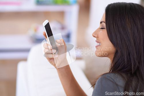 Image of Cellular smiles. an attractive young woman using her mobile phone at home.