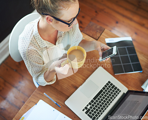 Image of Getting some work done from home today. A young woman using her cellphone while working from home.