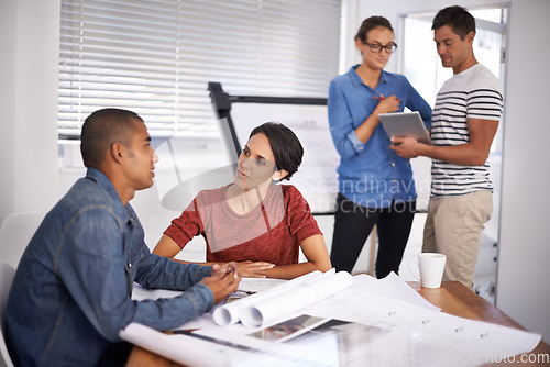 Image of Debating the design ensures its perfection. a group of young designers working together in an office.