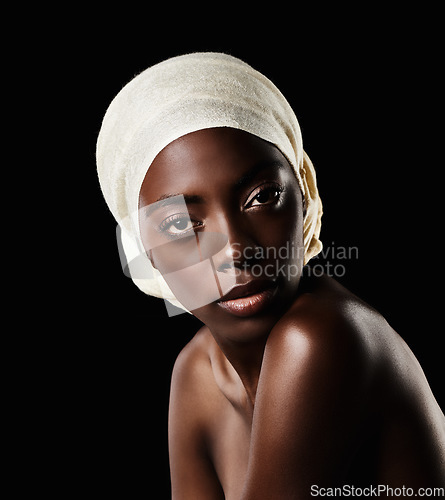 Image of Confident in her skincare regime. Studio shot of a beautiful woman wearing a headscarf against a black background.