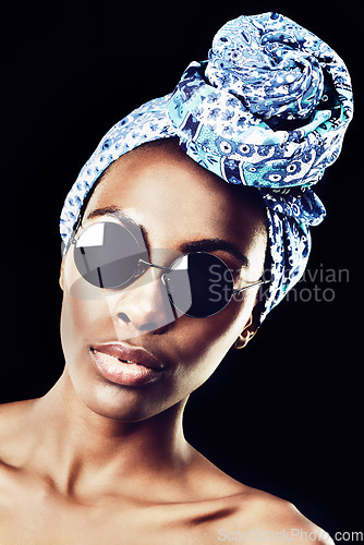 Image of Sophisticated in a scarf. Studio shot of a beautiful woman wearing a headscarf against a black background.
