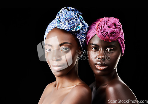 Image of Fashion is the art of self expression. Studio portrait of two beautiful women wearing headscarves against a black background.