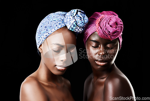 Image of Gorgeously glowing. Studio shot of two beautiful women wearing headscarves against a black background.