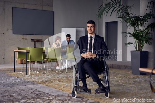 Image of Businessman in a wheelchair commands attention, symbolizing resilience and success amidst a dynamic modern office environment.