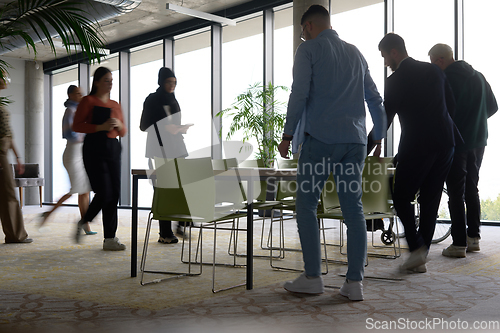 Image of A diverse group of business professionals gathers around a table for meetings, engaging in discussions, collaboration, and strategic planning in a modern office