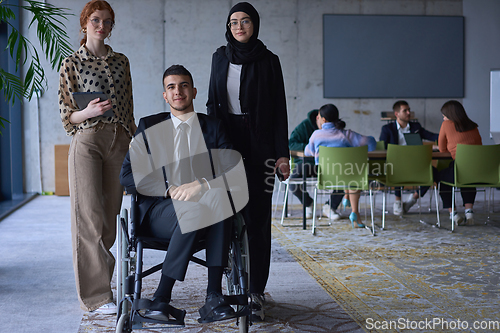 Image of A businessman with disability in a wheelchair is surrounded by supportive colleagues in a modern office, showcasing the strength of teamwork, inclusivity, and empowerment in the face of challenges.