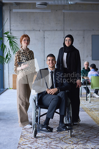 Image of A businessman with disability in a wheelchair is surrounded by supportive colleagues in a modern office, showcasing the strength of teamwork, inclusivity, and empowerment in the face of challenges.