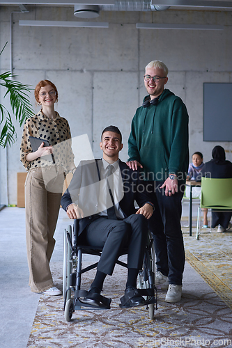 Image of A businessman with disability in a wheelchair is surrounded by supportive colleagues in a modern office, showcasing the strength of teamwork, inclusivity, and empowerment in the face of challenges.