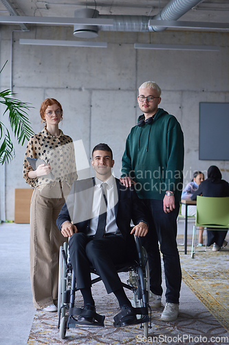 Image of A businessman with disability in a wheelchair is surrounded by supportive colleagues in a modern office, showcasing the strength of teamwork, inclusivity, and empowerment in the face of challenges.