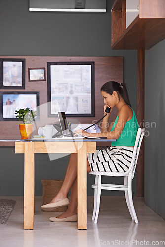 Image of Handling every aspect of her business from home. a young woman talking on the phone while working from home.