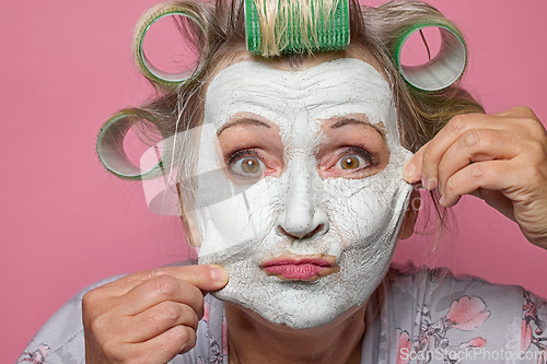 Image of funny senior women with clay face mask