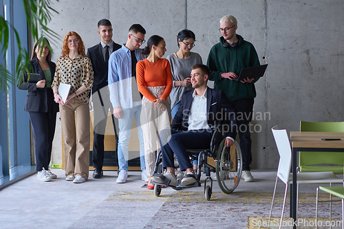 Image of Diverse group of business people, including a businessman in a wheelchair in a modern office