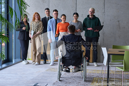 Image of A group of diverse entrepreneurs gather in a modern office to discuss business ideas and strategies, while a colleague in a wheelchair joins them.